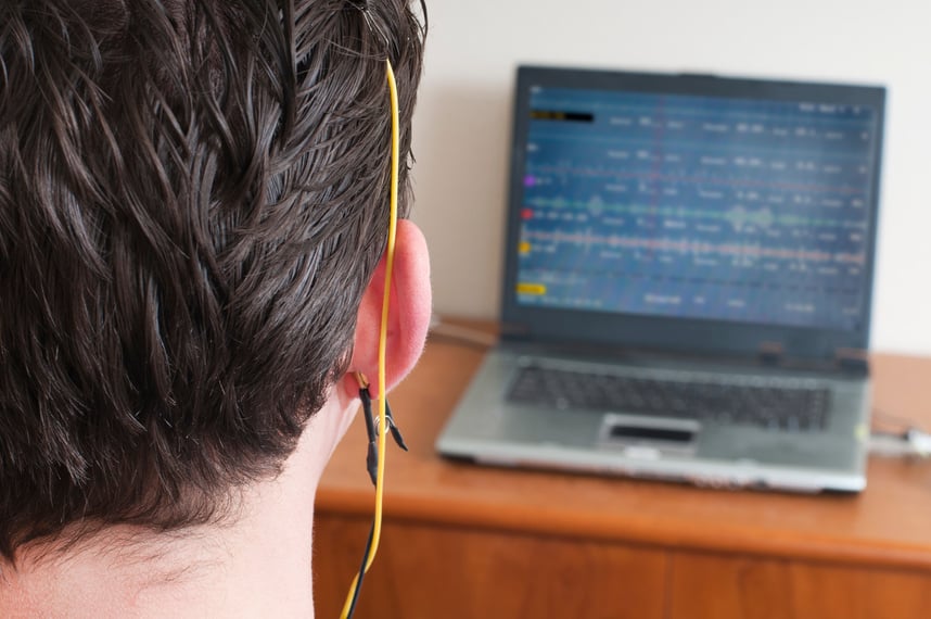 Rear of a neurofeedback patient and wire looking at a laptop